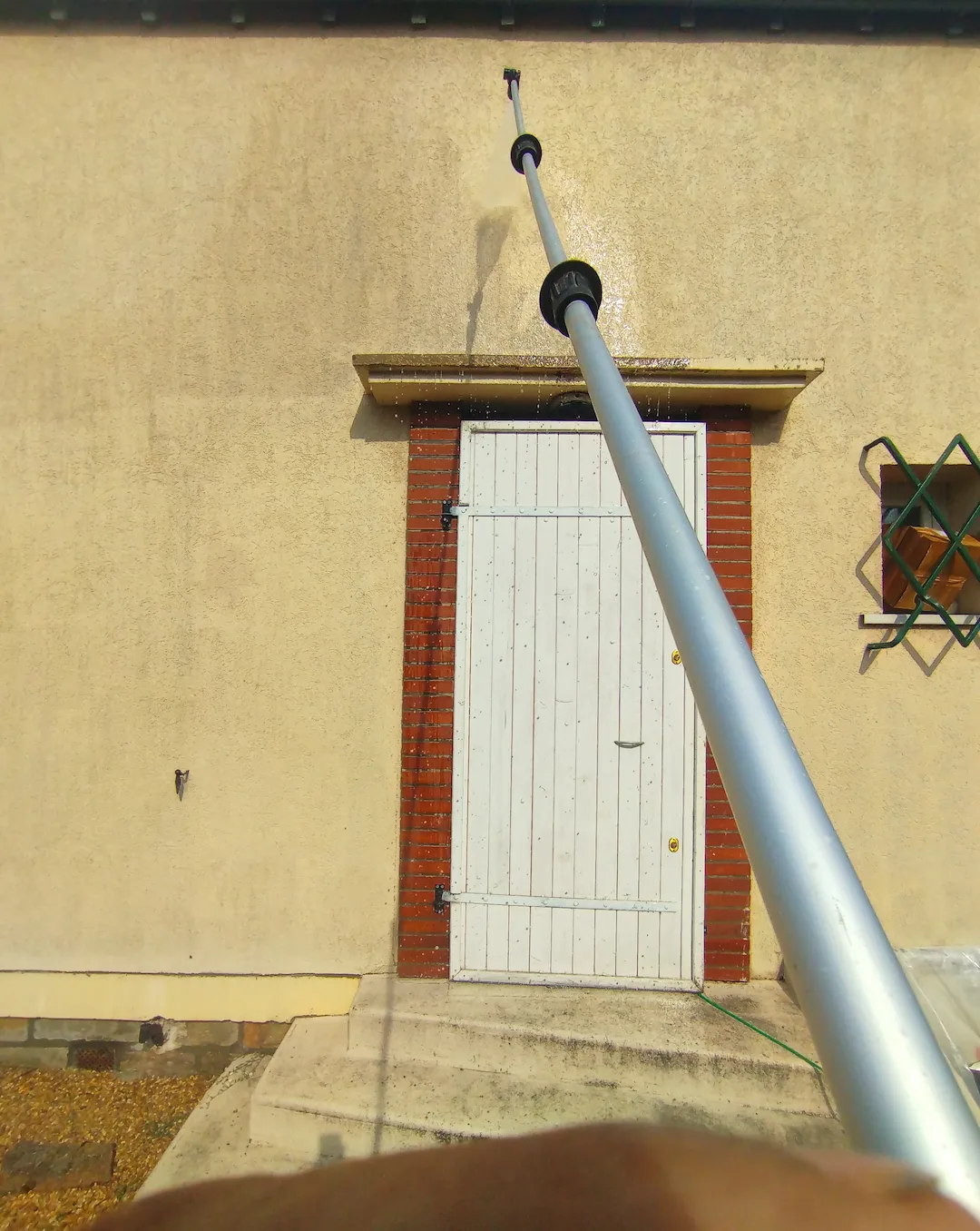 Pulvérisation en hauteur sur une façade avec une perche télescopique